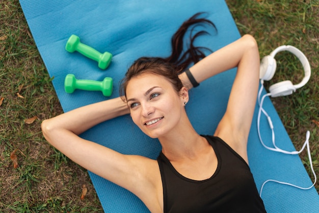 Bella donna di vista superiore che riposa sul tappeto di yoga