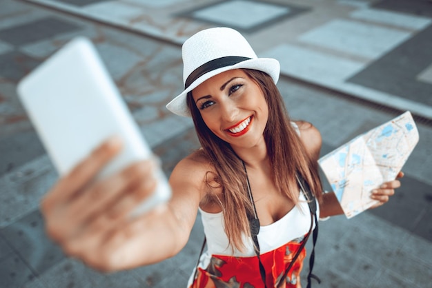 Top view on beautiful woman on vacation taking selfie with her smart phone. Selective focus.