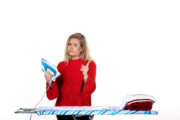 Photo top view of beautiful young woman holding iron pointing up with surprised facial expression on white background