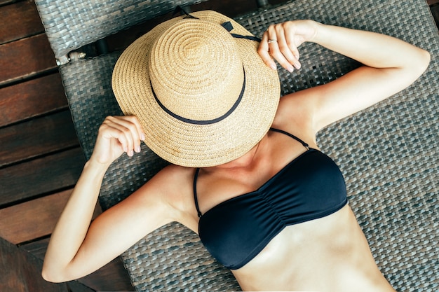 Top view of beautiful young woman relaxing in deck chair near the pool