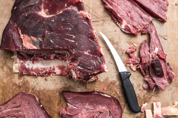 Top of view beef portioned steaks on wooden butcher board.