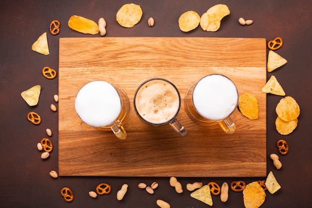 Top view beer with snacks on cutting board