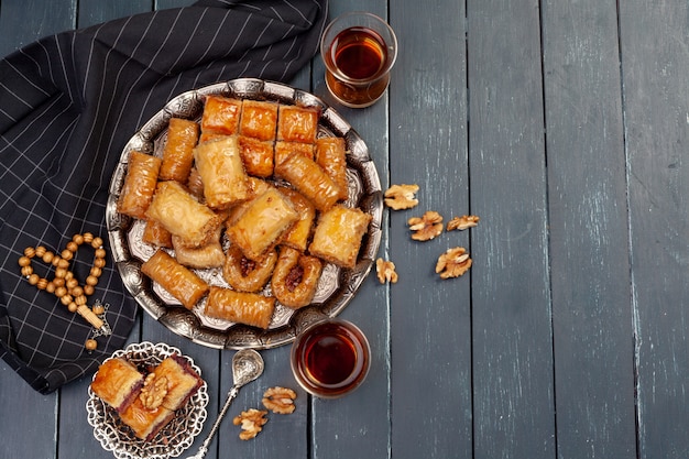 Top view of big metal tray with turkish baklava on planked wooden table