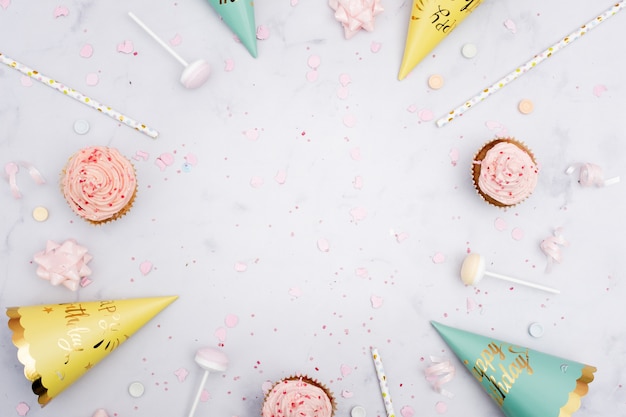 Vista dall'alto di coni di compleanno con cannucce e cupcakes