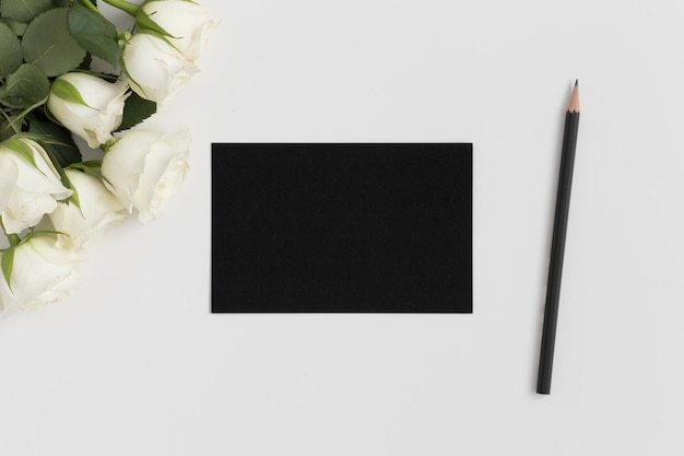 흰색 테이블에 장미 꽃다발이 있는 검은색 카드 흉내내기의 상위 뷰