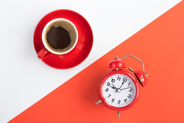 Top view of black coffee and red alarm clock