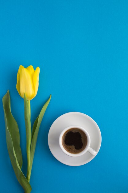 Vista dall'alto di caffè nero nella tazza bianca e un tulipano giallo