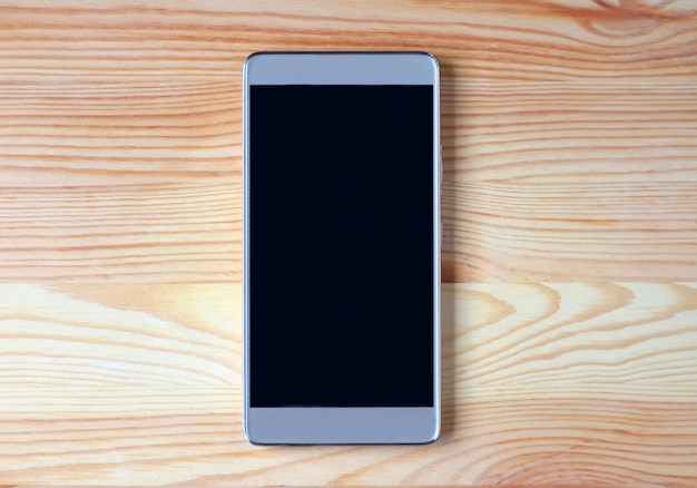 Top view of a black empty screen smartphone isolated on light brown wooden table