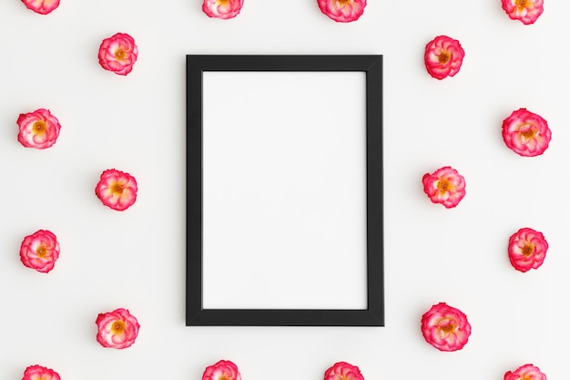 Top view of a black frame mockup with pink roses decoration on a white background