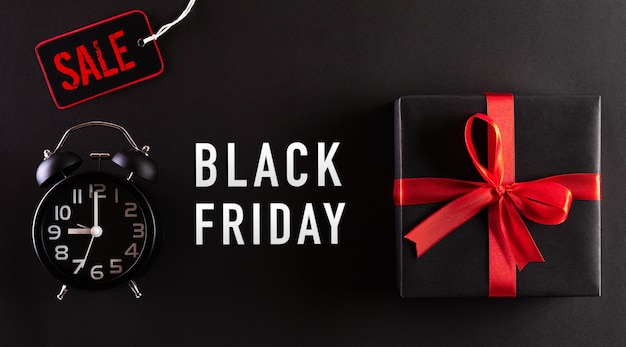 Top view of Black Friday Sale text with black gift box and alarm clock