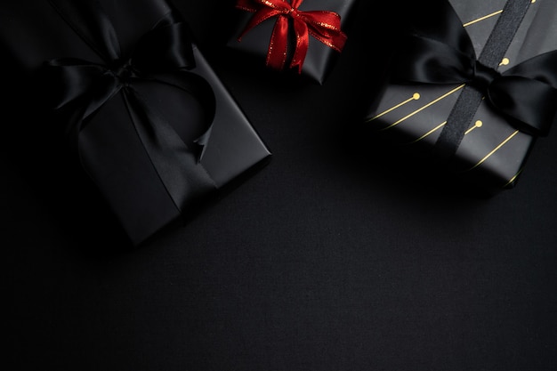 Top view of black gift box with red and black ribbons isolated on black