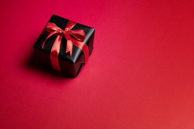 Top view of black gift box with red and black ribbons isolated on red background