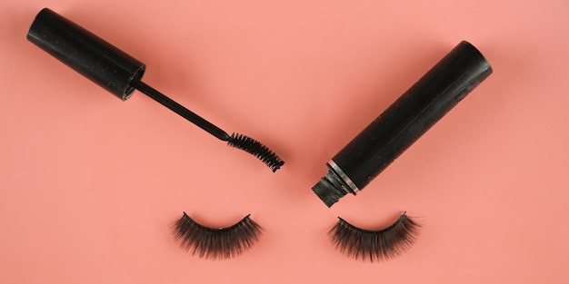 Top view black mascara and false eyelashes with pink background