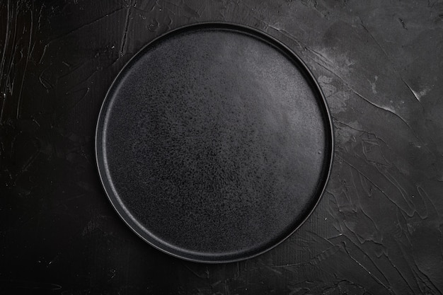 黒の暗い石のテーブルの背景に、黒のプレートセットの上面図