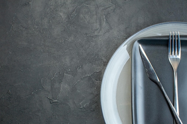 Top view black plate with fork knife and gray plate on dark background silverware diner colourful femininity hunger ladies cutlery