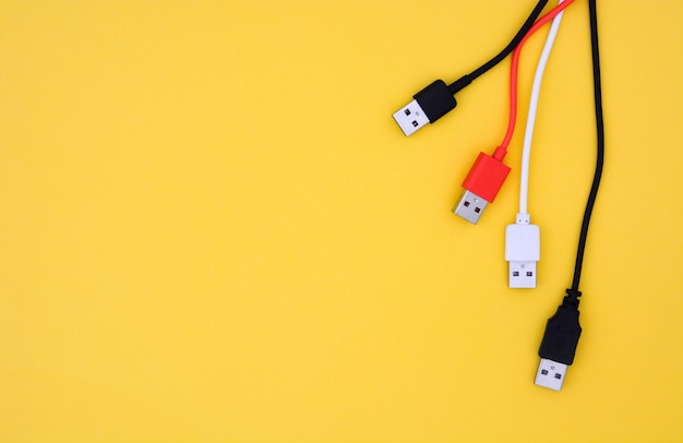 Top view black, white and red color USB cables on yellow background