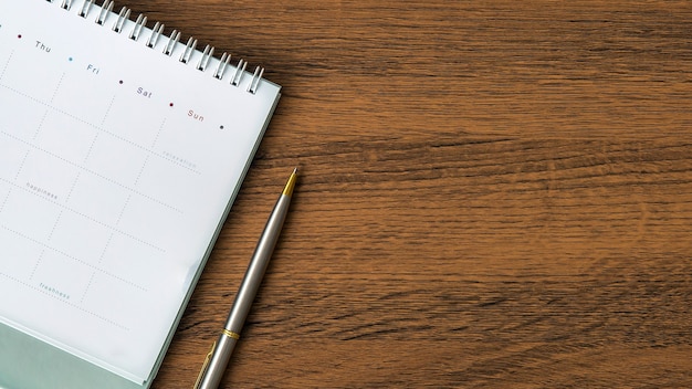 The top view blank calendar with a pen on desk