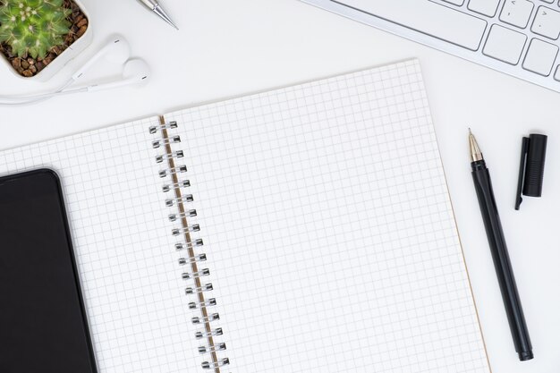 Top view of blank grid notebook page on top of white office table, flat lay.