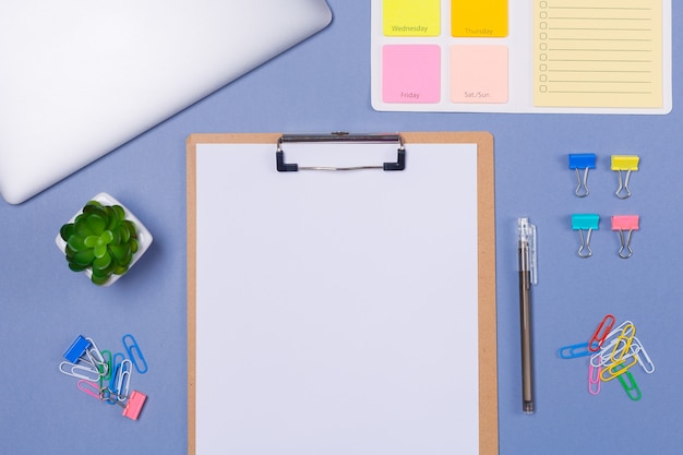 Top view of Blank list on clipboard, To do list for the week, pen, stationery and laptop on light purple background, flat lay.  Copy space. Free space. Schedule. Timetable.