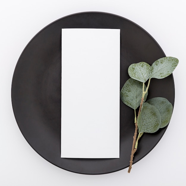 Top view of blank menu paper on plate with plant