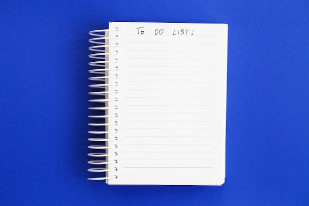 リストを行うために青い背景の上の空白のメモ用紙の上面図