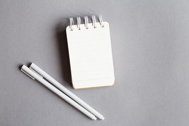 Top view of blank note paper with pen on gray background