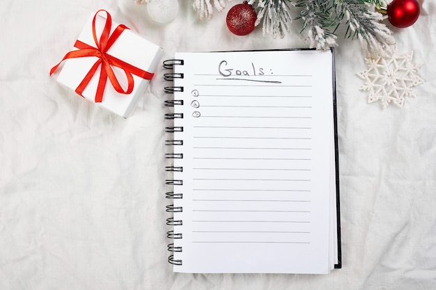 Top view of blank notebook for goals resolutions and christmas decoration on white textile linen