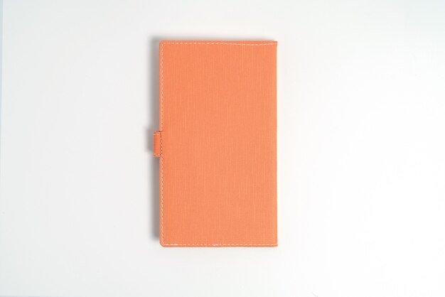 Top view blank orange leather diary on white desk