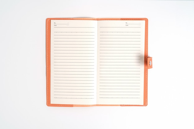 Top view blank orange leather diary on white desk