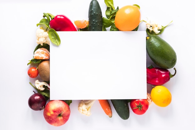 Foto vista superiore di carta bianca sopra verdure fresche e frutta su sfondo bianco