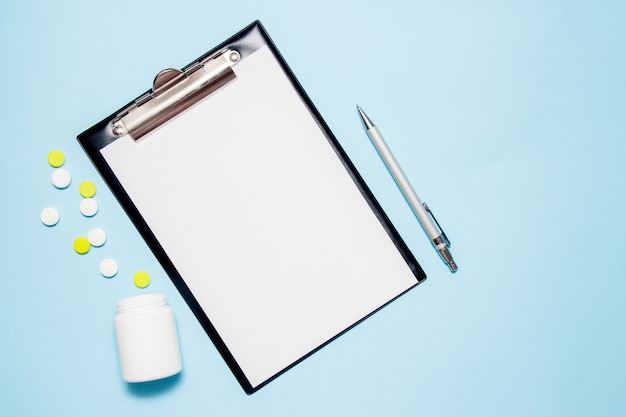 Photo top view of blank paper for writing doctor prescription. pills on blue