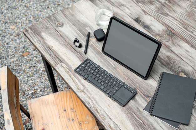 Top view of blank screen table with clipping path, keyboard, notebook and gadget on wooden table.