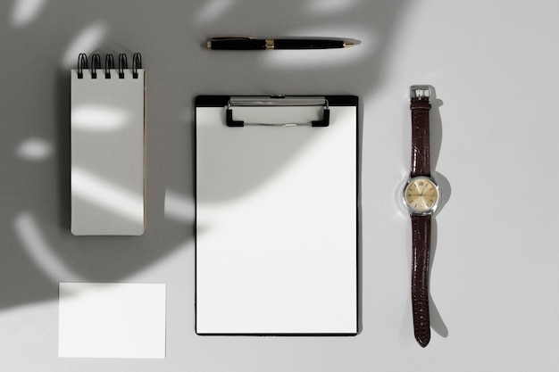 Top view of blank stationery, watch and pen on grey background