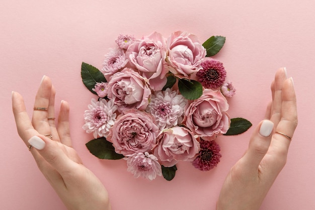 Top view of blooming spring flowers and female hands on pink background