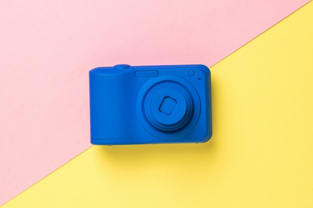 Top view of a blue camera on a yellow and pink background. Stylish equipment for photo and video shooting.