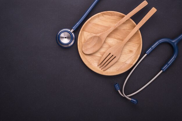 Top view blue doctor Stethoscope and set of spoon, fork and wooden dish