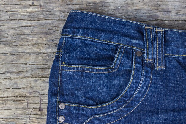 Top view of blue jeans on old wooden background.