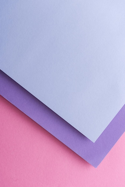 Top view of blue and purple sheets of paper on pink background with copy space