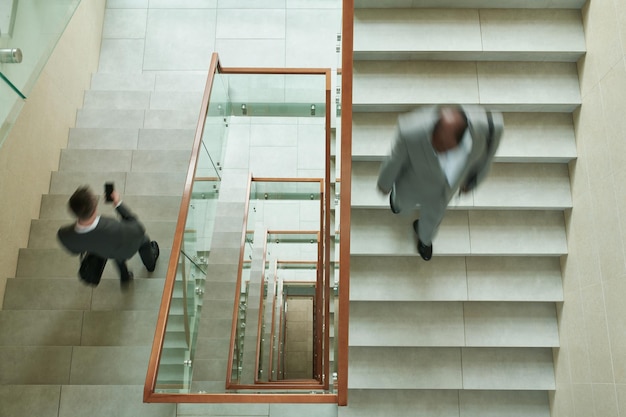 Top view of blurred intercultural businessmen walking downstairs