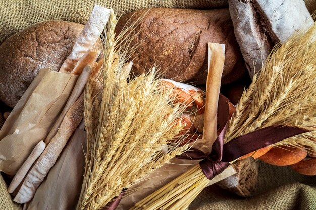 Foto vista dall'alto di un bouquet di grano disteso su pane fresco e altri prodotti da forno come simbolo del benessere alimentare e agrario del paese