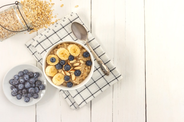 Top view of Bowl of oatmeal wirh blueberry and sliced banana on wooden table. Copy space,