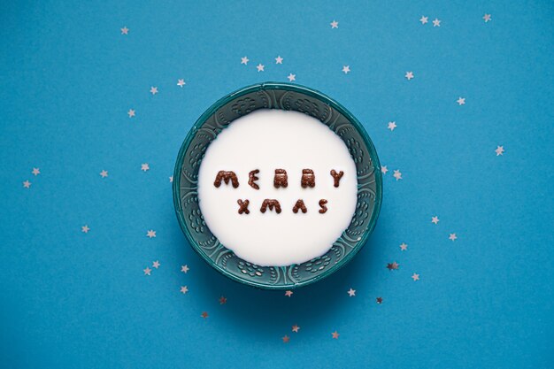 Top view of bowl with milk and chocolate alphabet cereals. Merry xmas text.