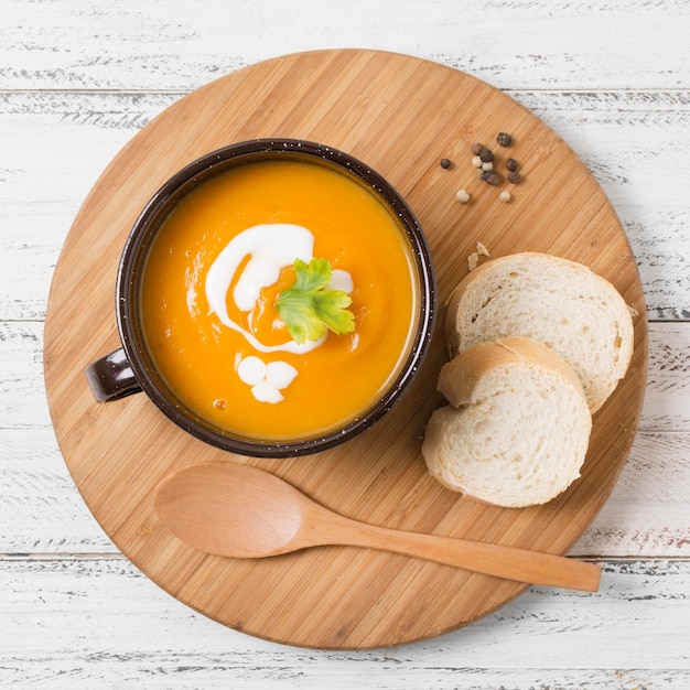 Photo top view bowl with pumpkin soup and bread