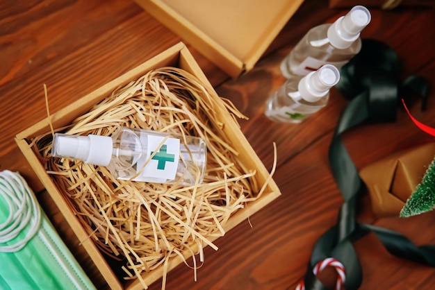 Top view of box of straw and antiseptic gift against coronavirus sanitizers medical masks and a sati...