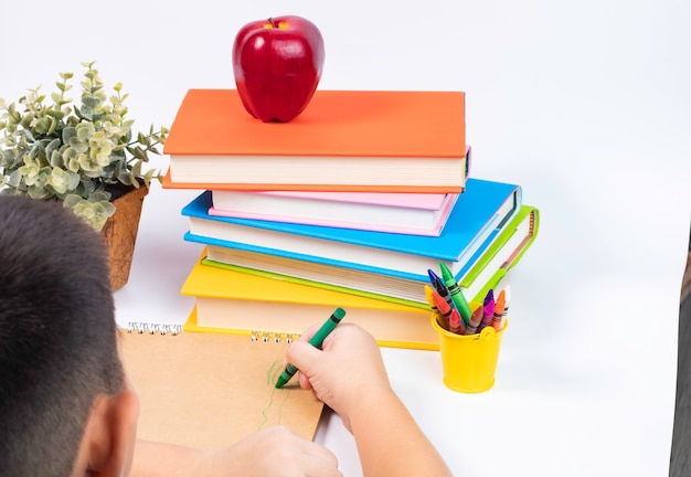 Photo top view boy drawing on blank sketchbook with stack of books/ back to school concept