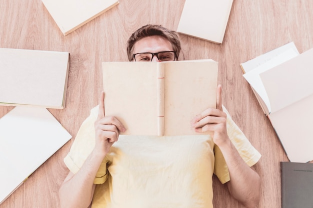 Una vista dall'alto di un ragazzo adolescente sdraiato sul pavimento e leggendo libri impara e studia