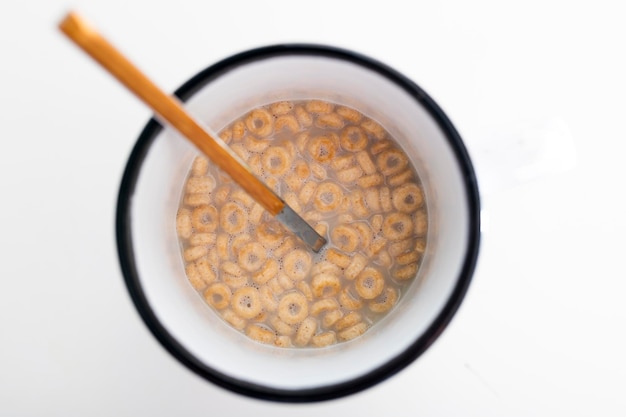 Top view of breakfast cup with oat milk and cereal cheerios