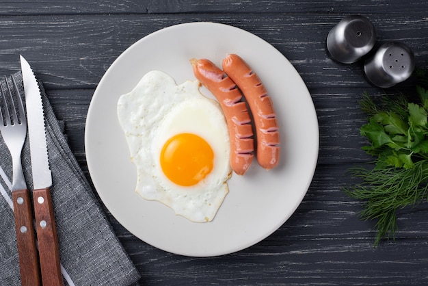 Vista superiore delle salsiccie di American National Standard dell'uovo di prima colazione sul piatto con le erbe