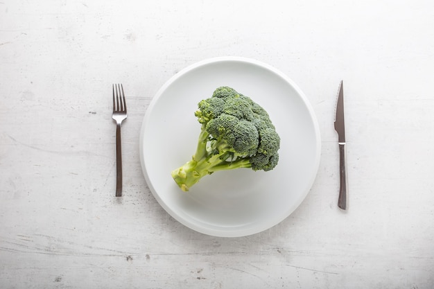 Top of view broccoli on plate with fork and knife.