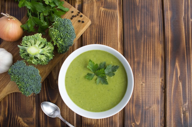 Top view of broccoli puree soup in the white bowl on the wood table